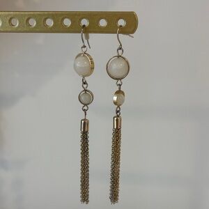 Gold toned dangle earrings with white cabochon-style stones and chain tassels